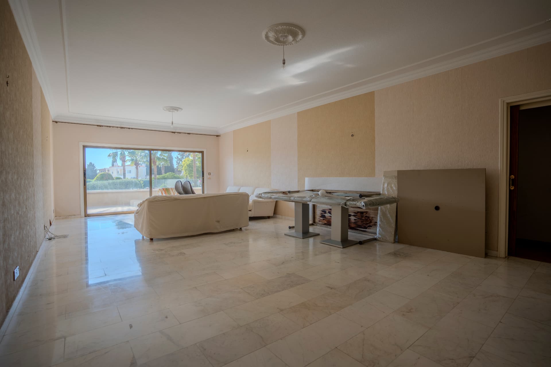 Unrenovated Apartment 3 living area with covered furnishings, marble floors, and terrace access