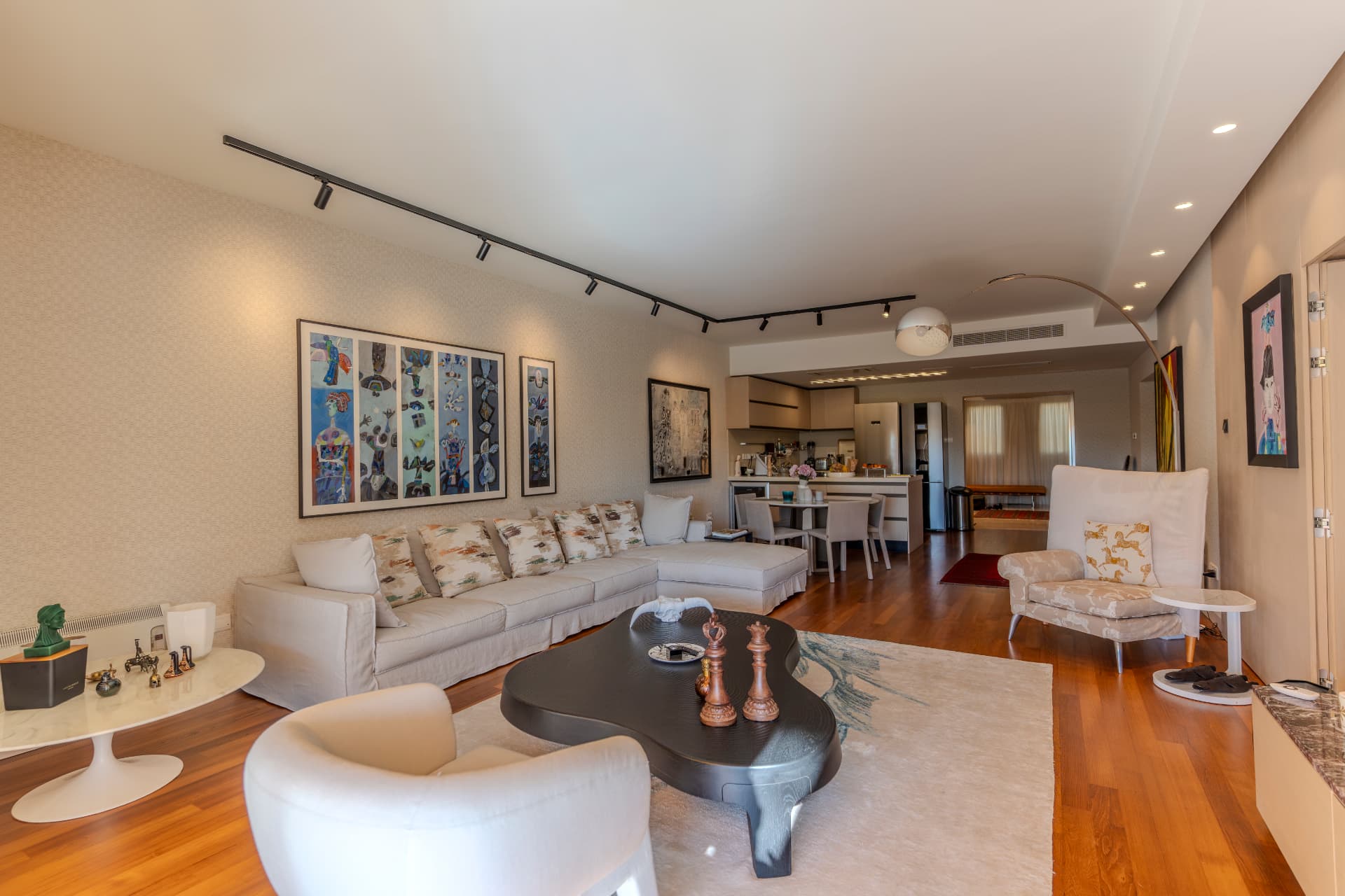 Bright renovated living room with beige sofas, curated artwork, and open-plan kitchen views